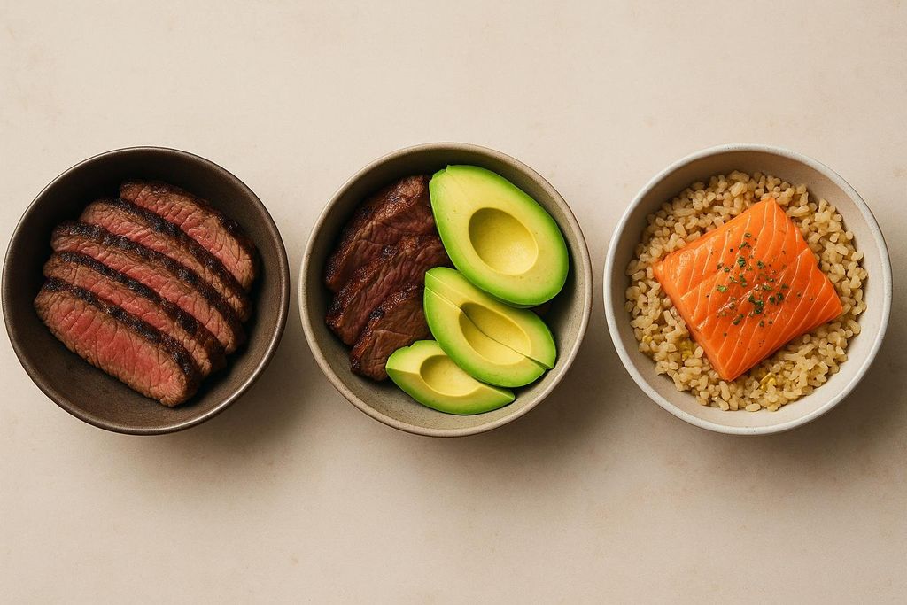 Three bowls on a light surface, each containing a different type of meal. From left to right: sliced steak, steak with avocado slices, and salmon over brown rice.