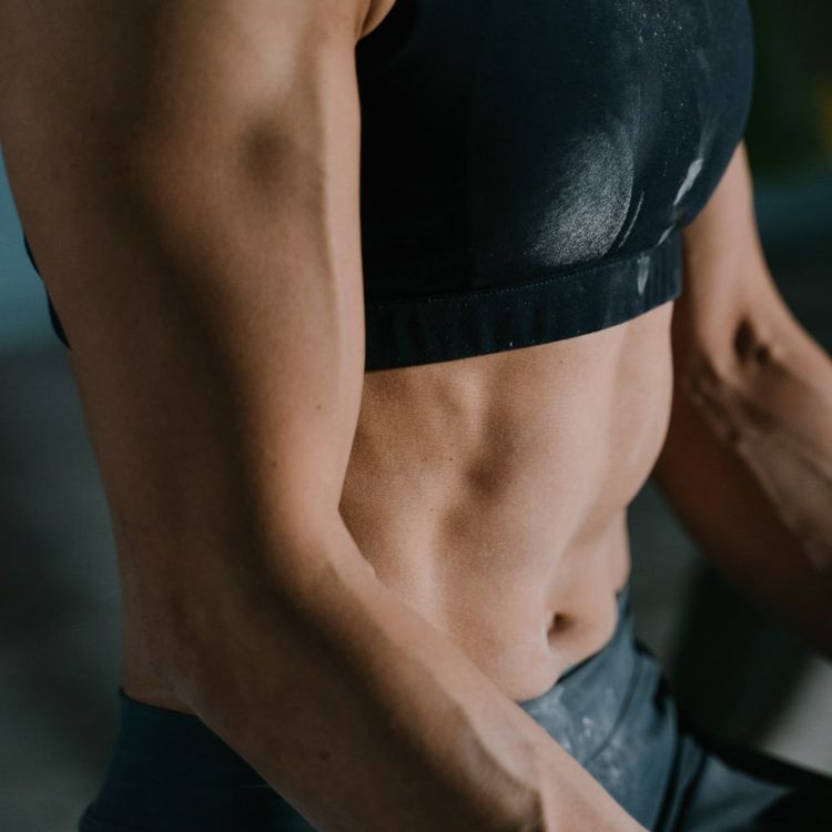 Close up of an athletic woman's muscular arms and abdomen.