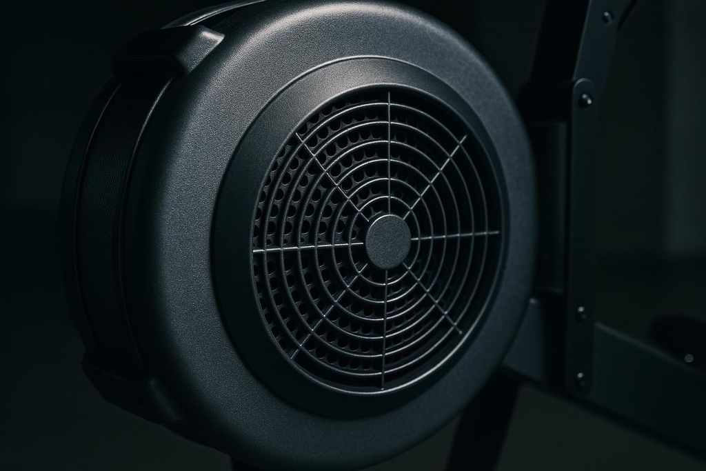 Close-up of the black plastic flywheel enclosure and fan of an indoor rowing machine.