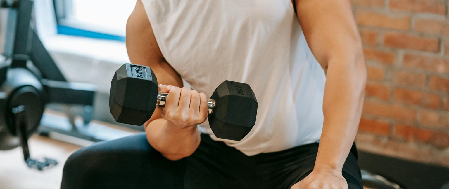 Cropped shot of a person lifting a dumbbell with a 20lb weight in a gym setting.