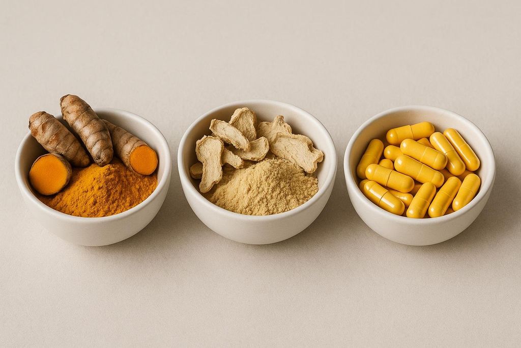 Three bowls displaying anti-inflammatory options: whole turmeric roots and turmeric powder, dried ginger pieces and ginger powder, and yellow vitamin C capsules.