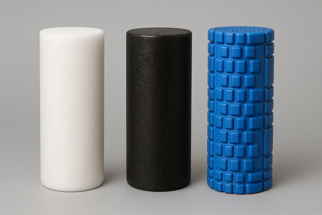 Three foam rollers of different colors and textures, representing soft, medium, and high-density options. From left to right, a white and smooth roller, a black and slightly textured roller, and a blue roller with a textured grid pattern.