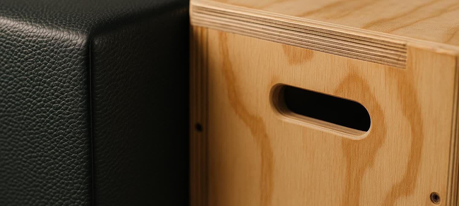 Close-up photo comparing the surface texture of a black foam plyo box and a light-colored wooden plyo box. The foam box has a pebbled, textured surface, while the wooden box shows the grain of the wood and distinct layers of plywood.