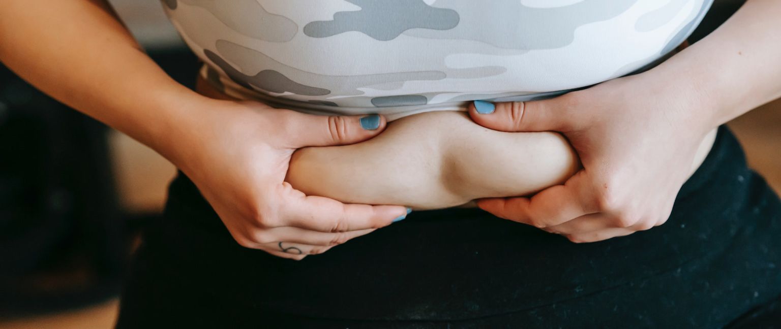 A close-up shot of a person squeezing the fat on their waist.