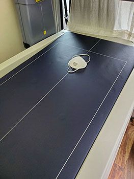 An N95 mask rests on a dark blue scanning table in a medical setting.