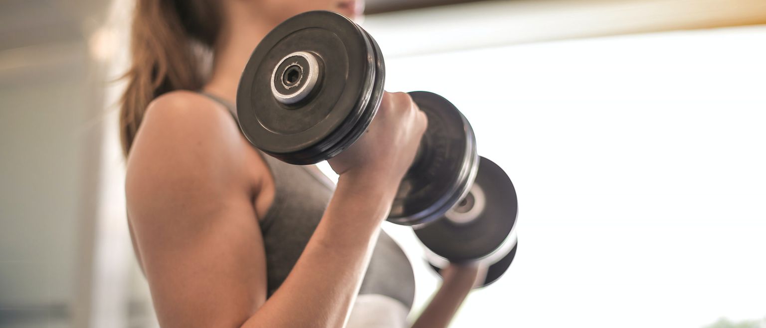 A woman lifting dumbbells during a workout, focusing on muscle building.