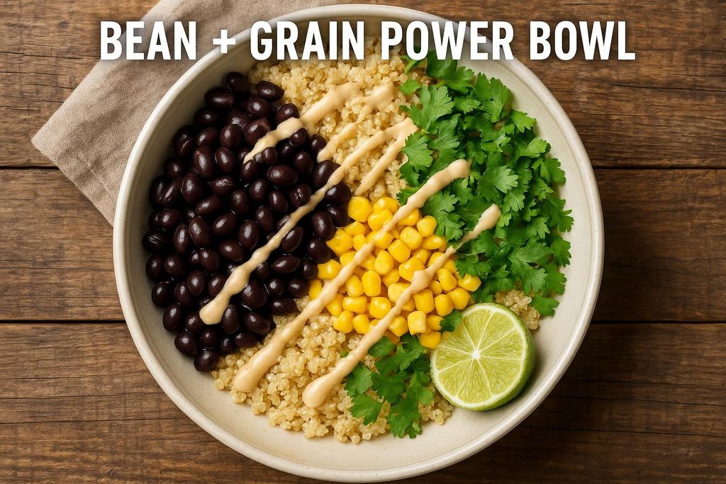 An overhead shot of a vibrant bean and grain power bowl featuring black beans, quinoa, corn, cilantro, a creamy sauce, and a lime wedge. The text 'BEAN + GRAIN POWER BOWL' is superimposed on the image.