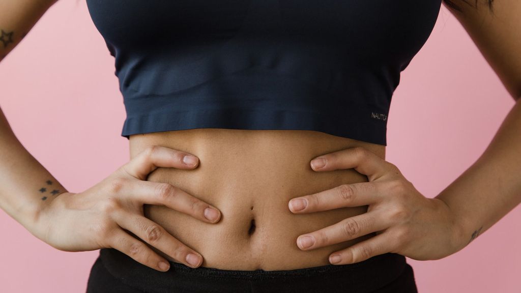 Close up shot of a person's hands resting on their abdomen.