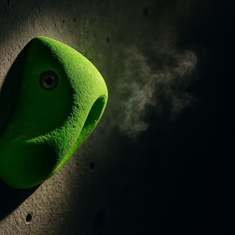 Backlit boulderer focused on a steep wall