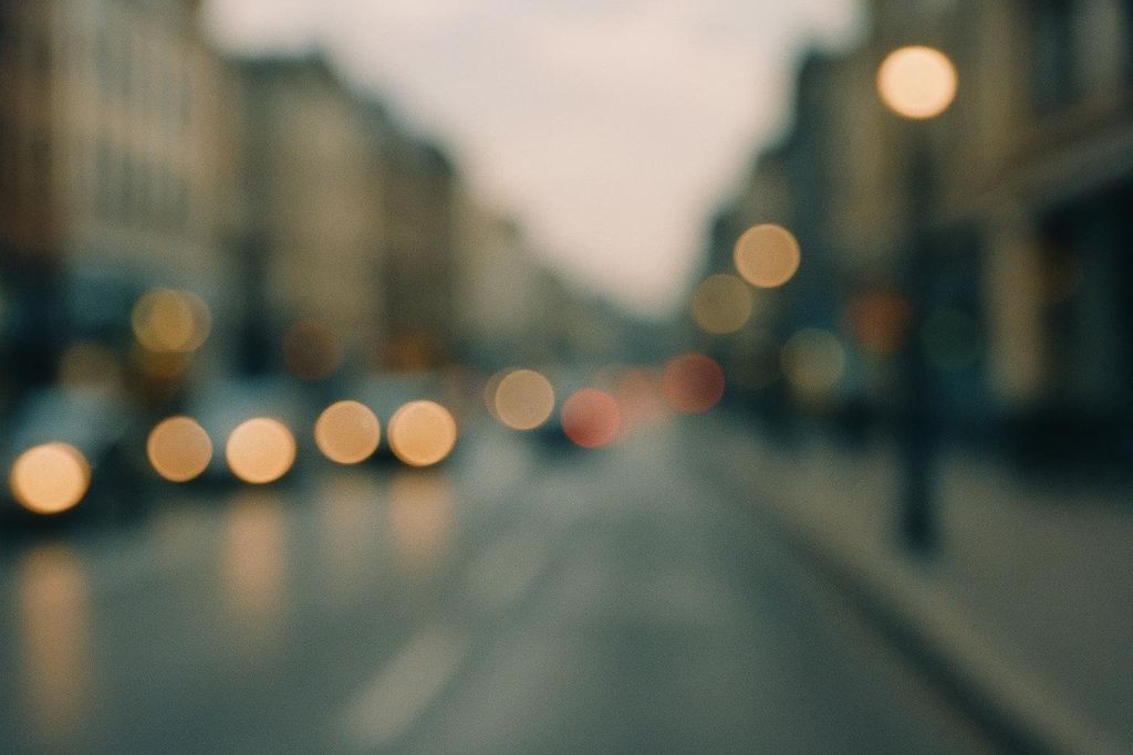 An intentionally blurred image of a city street at dusk, with abstract bokeh lights from car headlights and streetlights.