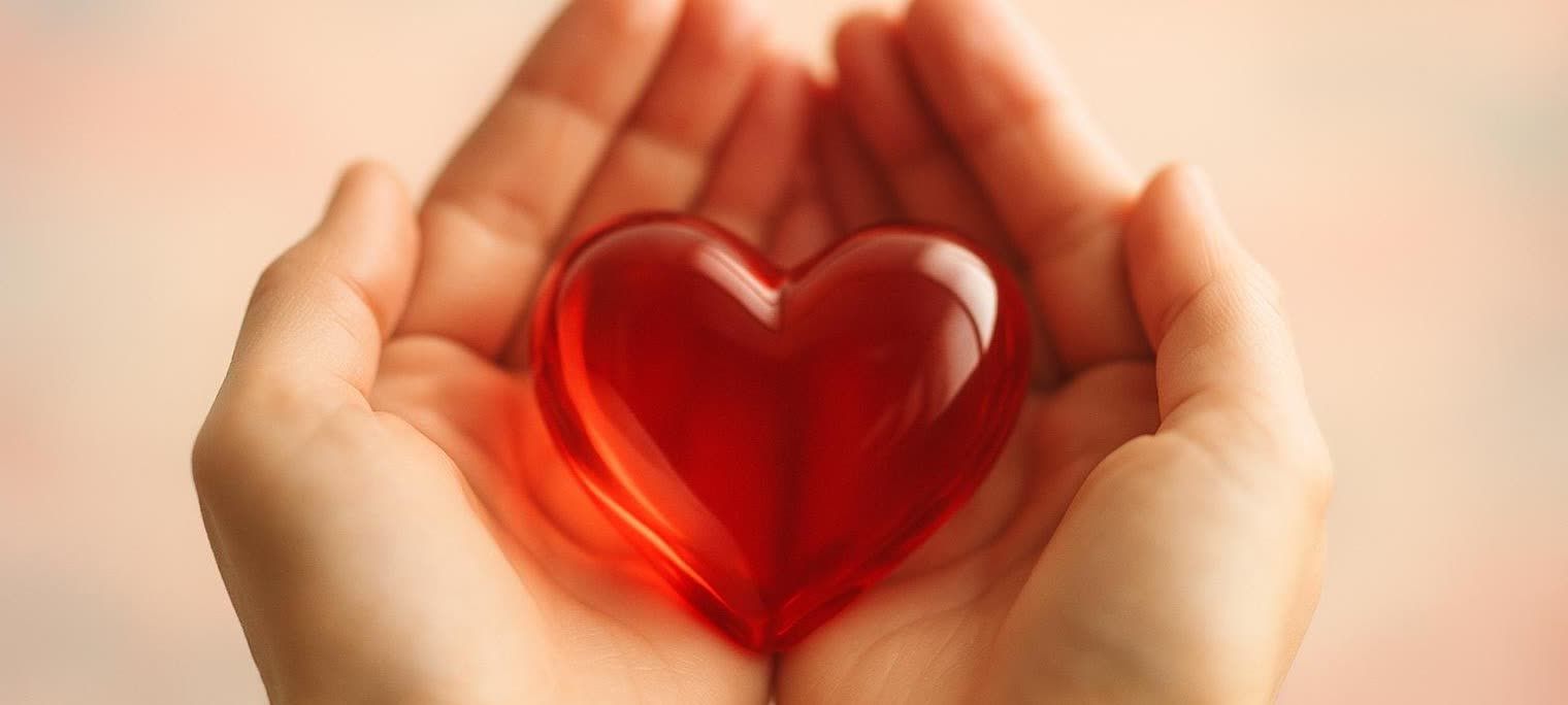 A smooth glass heart securely held in cupped hands