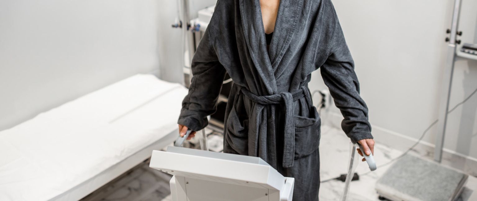 Woman wearing a grey robe and standing on an InBody scale for body composition analysis.