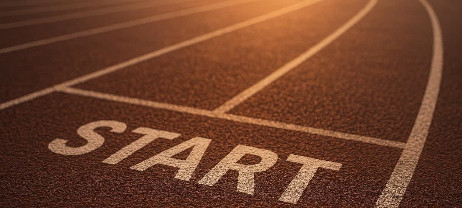 Close-up of a running track with the word 'START' clearly visible, illuminated by the warm light of a sunrise or sunset.