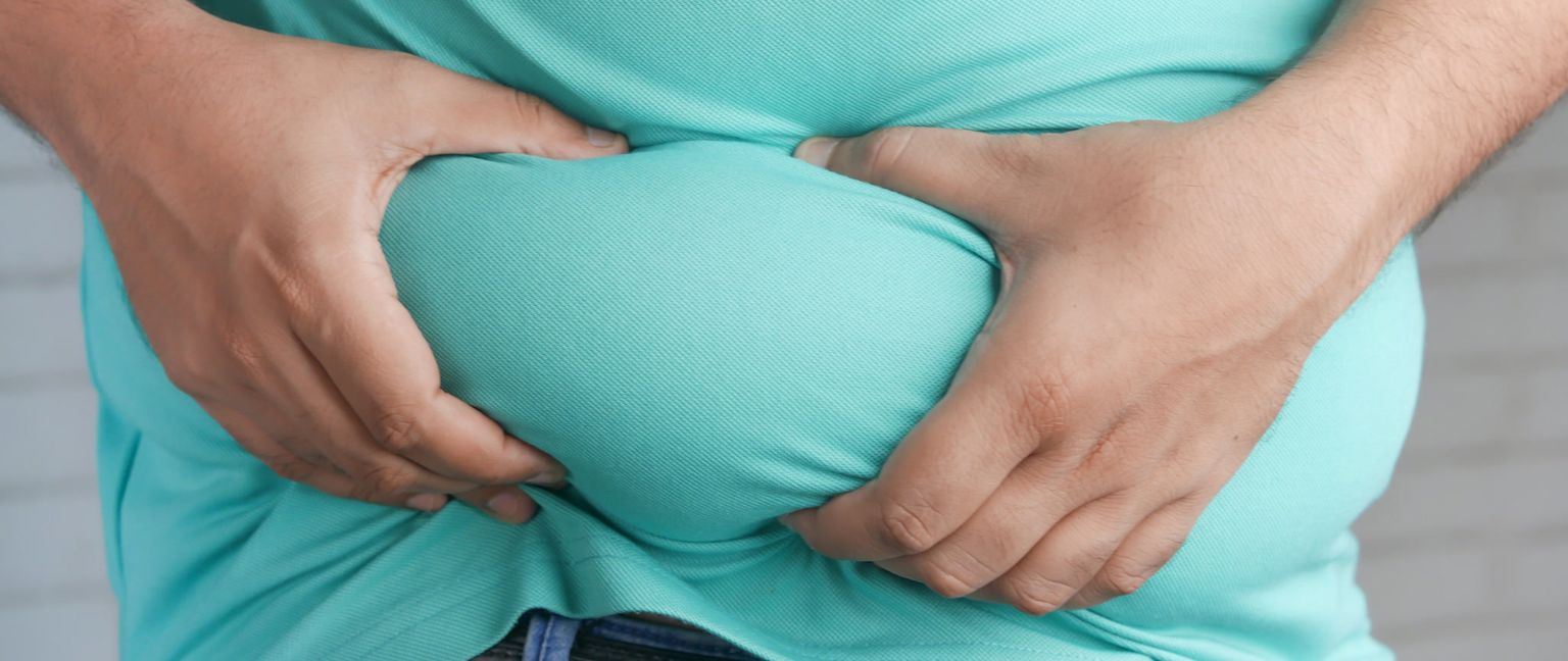 Close up of a man's hands squeezing his belly fat.
