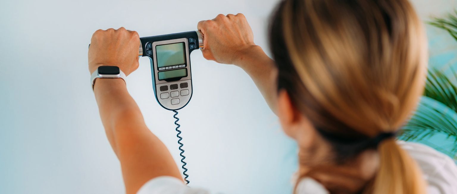 A woman holds up a body composition scale to measure her body fat percentage.